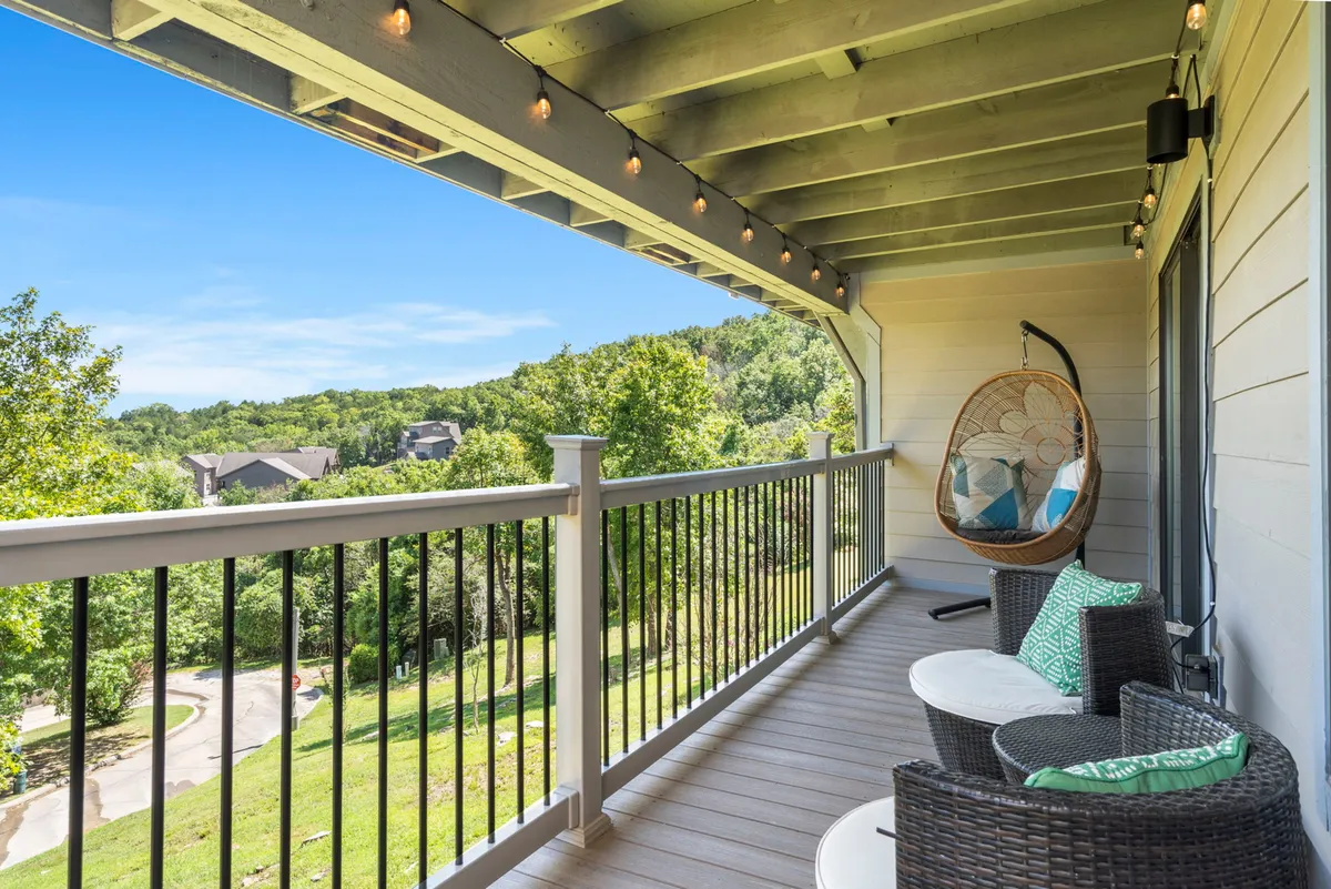 An inviting exterior deck area featuring a hanging chair, outdoor seating, decorative lights, and panoramic views of the surrounding landscape. The tranquil setting is perfect for socializing, enjoying sunrise coffees or evening drinks, and taking in the changing scenery.