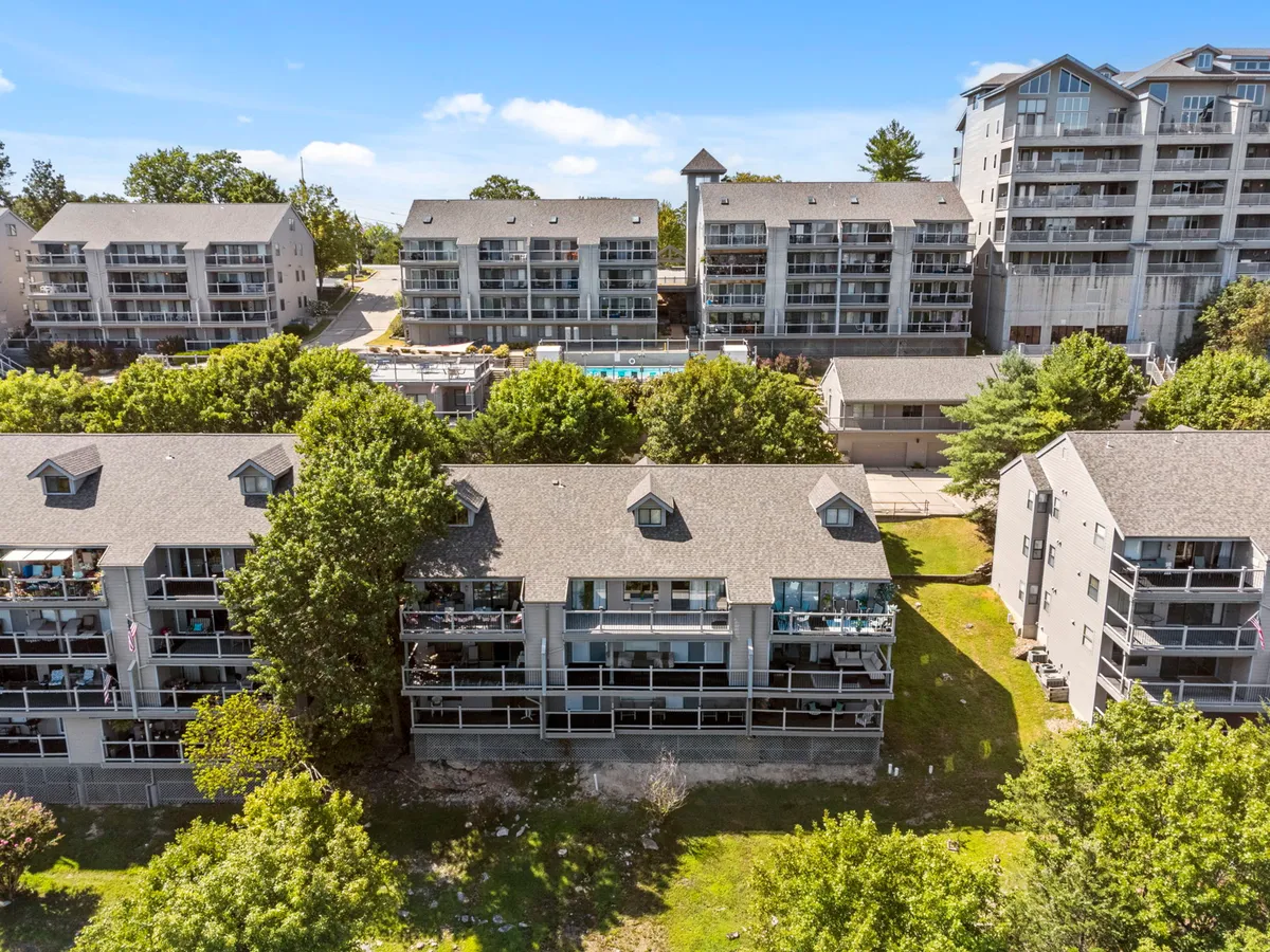 A vibrant community pool surrounded by green landscaping and apartment buildings. Group seating and balconies invite guests to gather, relax poolside, and enjoy sunny afternoons together in a lively, social atmosphere.