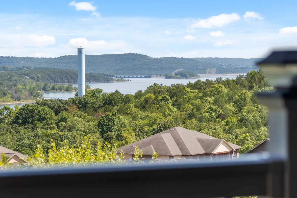 This image captures a sweeping sunset view over Table Rock Lake, framed by rolling mountains and lush trees, with a few lakeside buildings visible. The serene water reflects the sky’s changing colors, creating a tranquil yet inspiring scene that suggests opportunities for boating, picnicking, and relaxing by the water.