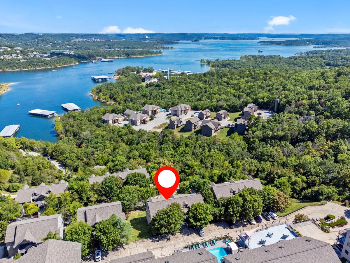 A peaceful exterior scene showing residential buildings, greenery, the swimming pool, and a glimpse of the lake beyond. The harmonious blend of outdoor amenities and natural beauty sets a tranquil mood for relaxation and recreation.